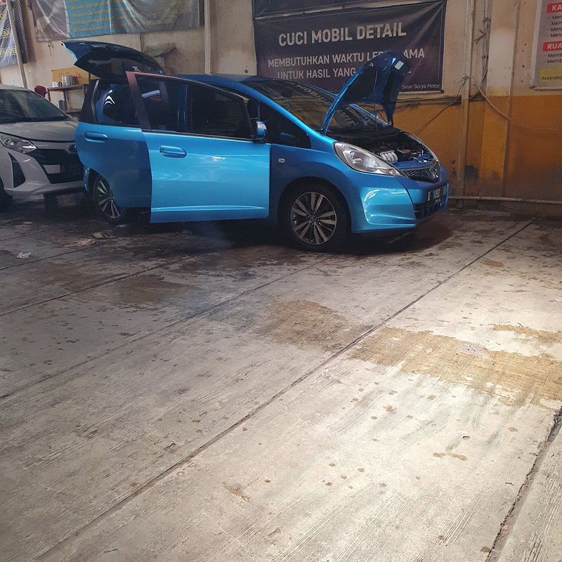 Mobil pelanggan dengan pintu terbuka saat proses detailing di dalam bengkel Sinar Surya Auto Care