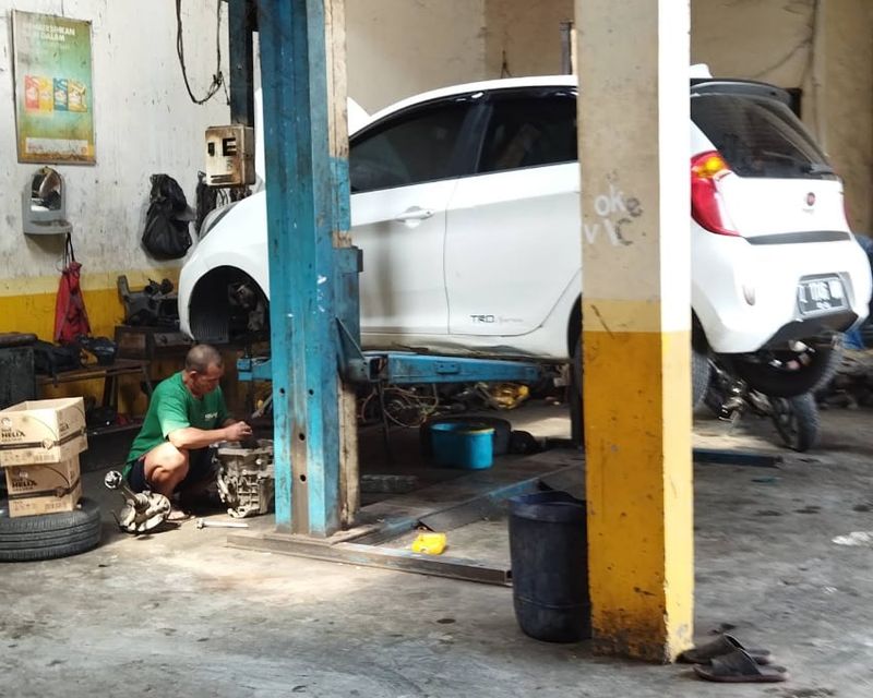 Mekanik Sinar Surya Auto Care memperbaiki komponen mobil di atas lift